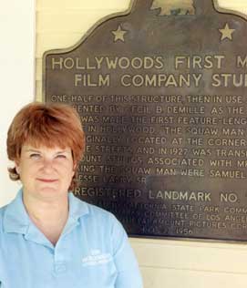Betty Petit standing in front of the Hollywood Heritage Museum's Landmark designation plaque.